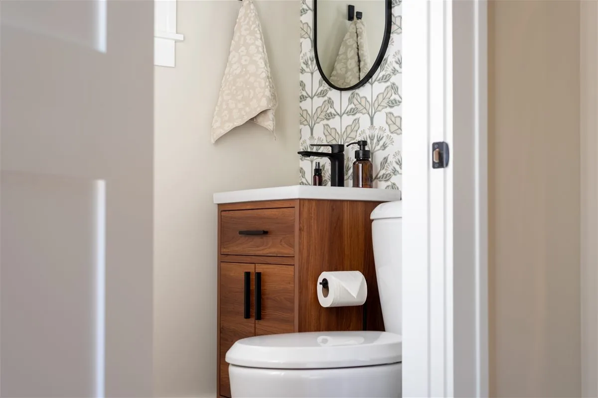 Small cosmetic bathroom refresh with updated vanity, wallpaper, modern faucet, and toilet.