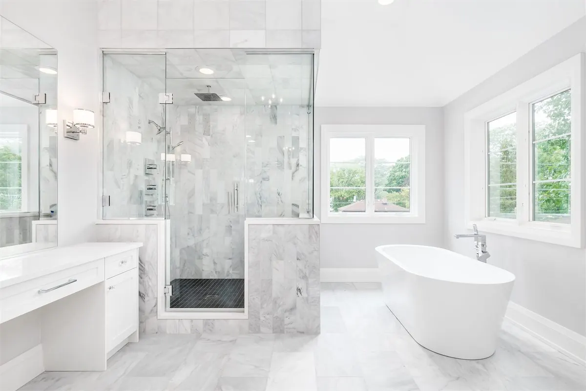 Custom bathroom remodel in Tacoma WA with marble-look tile shower, frameless glass doors, freestanding tub, and white vanity